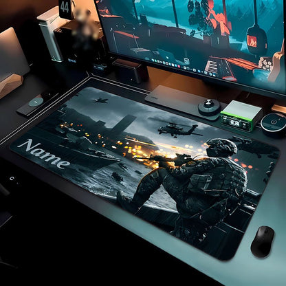 Tappetino per scrivania Deskzone™ AeroForce con una scena di azione militare: un soldato in primo piano spara da una barca in movimento, con elicotteri e esplosioni sullo sfondo in un ambiente urbano e nuvoloso. Il tappetino è posizionato su una scrivania da gaming con monitor, tastiera e mouse.
