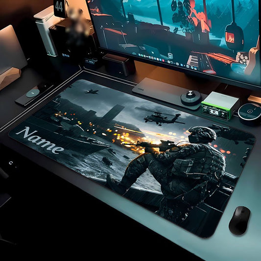 Tappetino per scrivania Deskzone™ AeroForce con una scena di azione militare: un soldato in primo piano spara da una barca in movimento, con elicotteri e esplosioni sullo sfondo in un ambiente urbano e nuvoloso. Il tappetino è posizionato su una scrivania da gaming con monitor, tastiera e mouse.