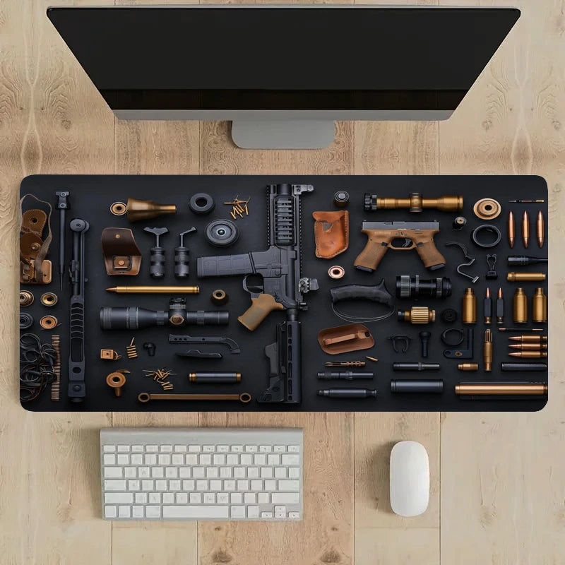 Vista dall’alto di una scrivania deskzone in legno con un ampio tappetino nero su cui sono disposti ordinatamente componenti di fucili e pistole, munizioni e ottiche, con monitor sopra, tastiera e mouse bianchi in basso.

