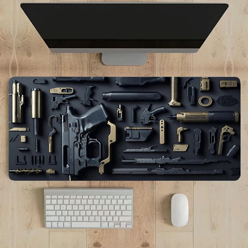 Scrivania in legno con monitor, tastiera e mouse su tappetino deskzone decorato con una dettagliata esplosione schematica di componenti di arma da fuoco, tra cui pistola, caricatori e silenziatore.