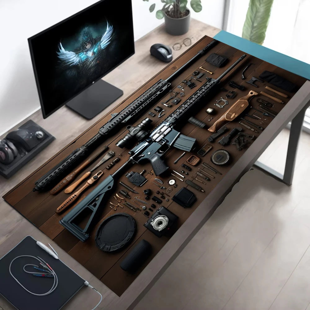 Scrivania deskzone con monitor che mostra una figura alata, tastiera e mouse su tappetino illustrato con ingranaggi e componenti meccanici, accanto a cuffie e taccuino.