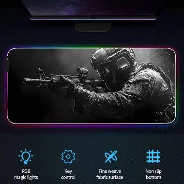 Tappetino mouse gaming RGB extra-large con design di guerra urbana, che mostra un soldato armato, elicotteri e veicoli militari, su una postazione da gioco illuminata.